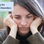 Woman with an autoimmune disorder holding her head in her hands while seated