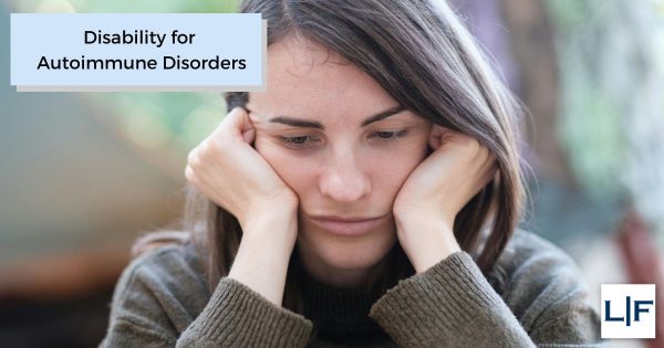 Woman with an autoimmune disorder holding her head in her hands while seated